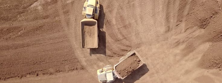 overhead view of two tractors are moving dirt